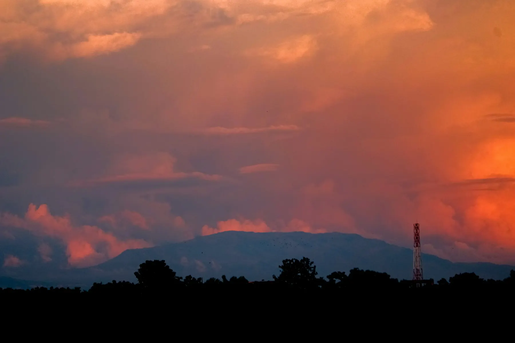 A fiery orange sunset over hazy hills